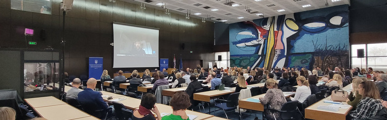 Hibridna konferencija s prevoditeljskom kabinom i zaslonom koji prikazuje internetsku platformu