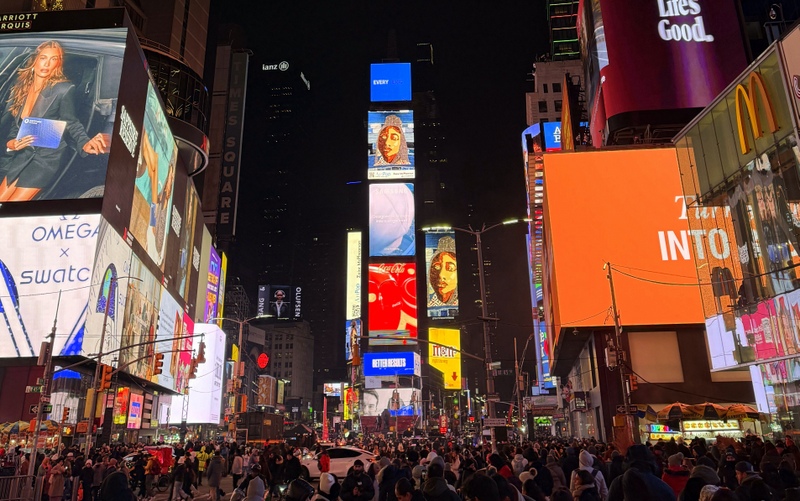 Times Square at night, crowded with people, with shiny ads everywhere
