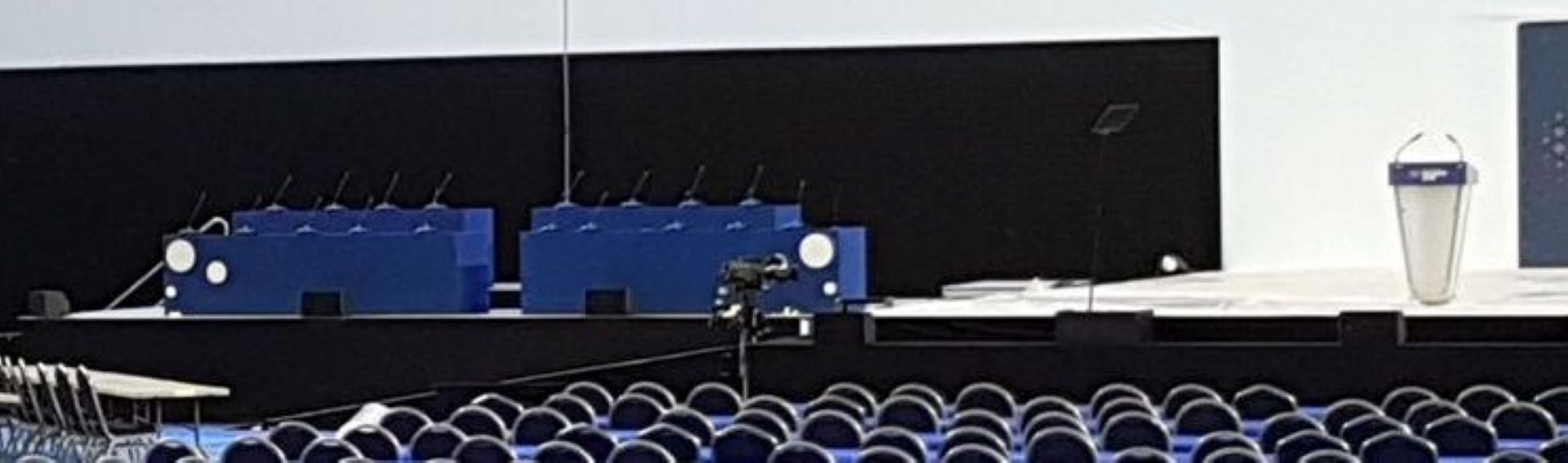 empty conference room stage showing presiding table and lectern with fixed microphones