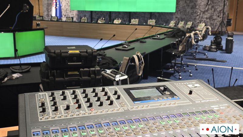 Soundcraft mixing console at a conference, with the speakers’ microphones on the table beyond